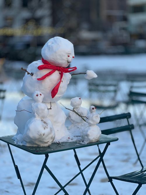 Free Adorable snowmen and snow babies on a table in a snowy park, evoking winter charm. Stock Photo