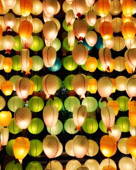 Vibrant paper lanterns hang aglow at a nighttime festival scene.