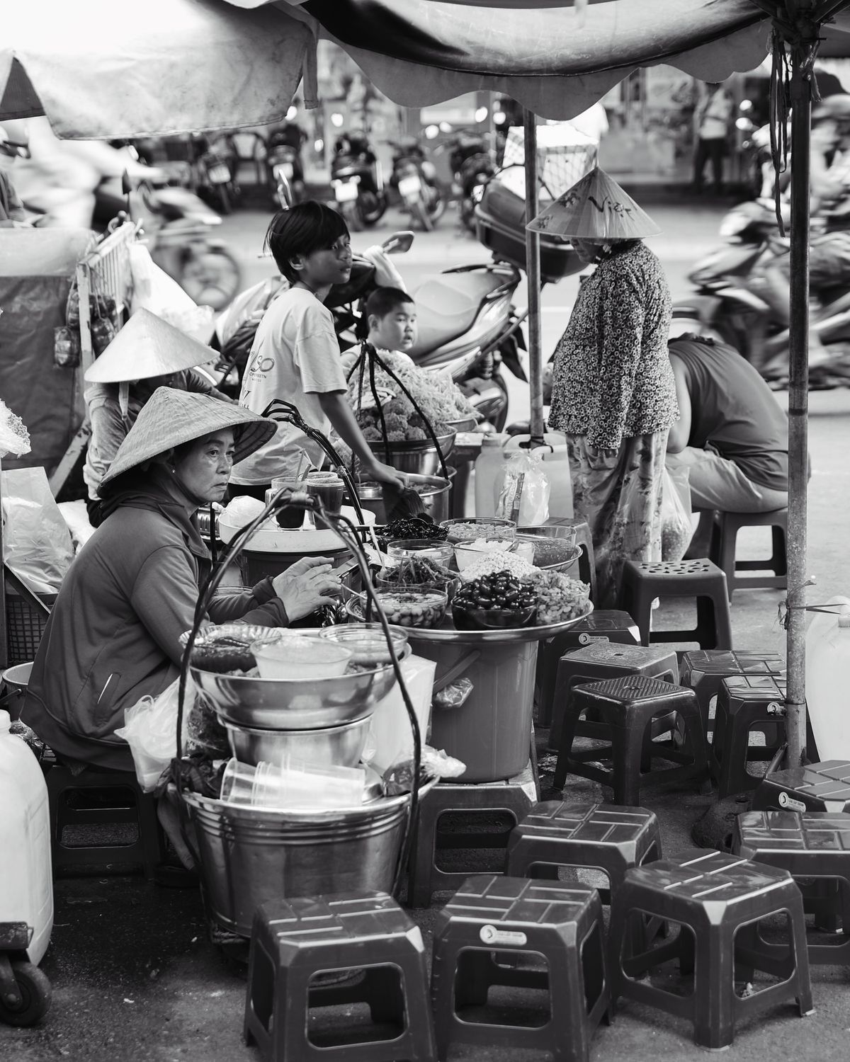 A crowded street market with vendors and conical hats