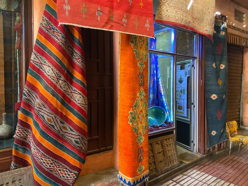 Vibrant handmade rugs hanging in a Taroudant market showcasing Moroccan craftsmanship.
