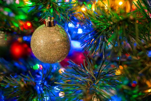 Free Colorful Christmas tree adorned with a sparkling ornament and vibrant lights. Stock Photo