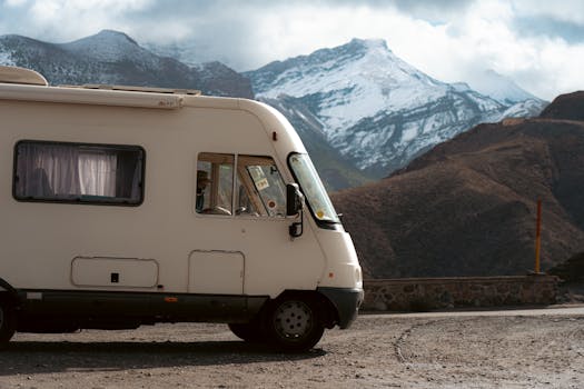 Camper van parked on a road with snow-capped mountains in the background, offering an adventurous travel scene.