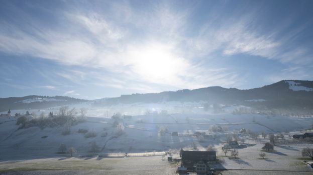 Scenic winter view of Altendorf, Switzerland with sunlit snowy hills.