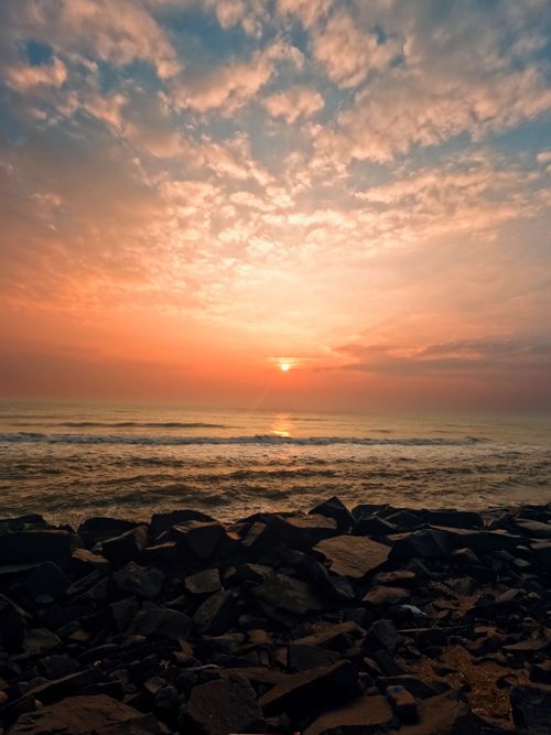 Free Breathtaking view of a sunset over the ocean with rocks in the foreground. Stock Photo