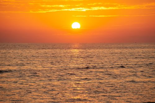 Free Stunning sunset over the ocean with a vivid golden glow, creating a beautiful seascape. Stock Photo
