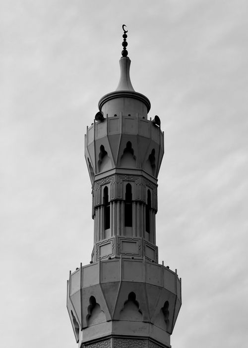 Free Black and white photograph of a mosque minaret silhouetted against a cloudy sky. Stock Photo