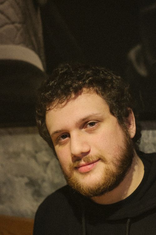 Free A warm portrait of a bearded man with curly hair indoors, showcasing a relaxed and candid expression. Stock Photo