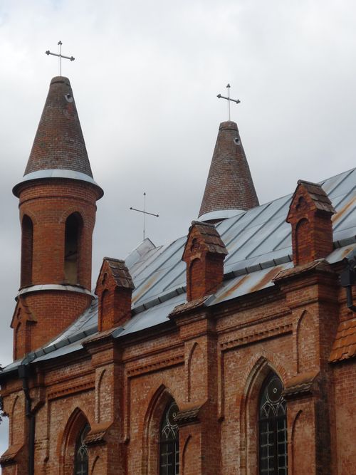 Free Red brick church with Gothic architecture and crosses, under cloudy sky. Stock Photo