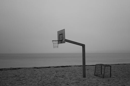 A solitary basketball hoop on a foggy beach evokes a sense of calm and introspection.