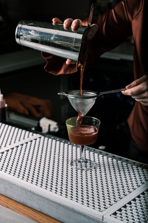Free Bartender straining a classic cocktail at bar counter. Perfect for lifestyle content. Stock Photo