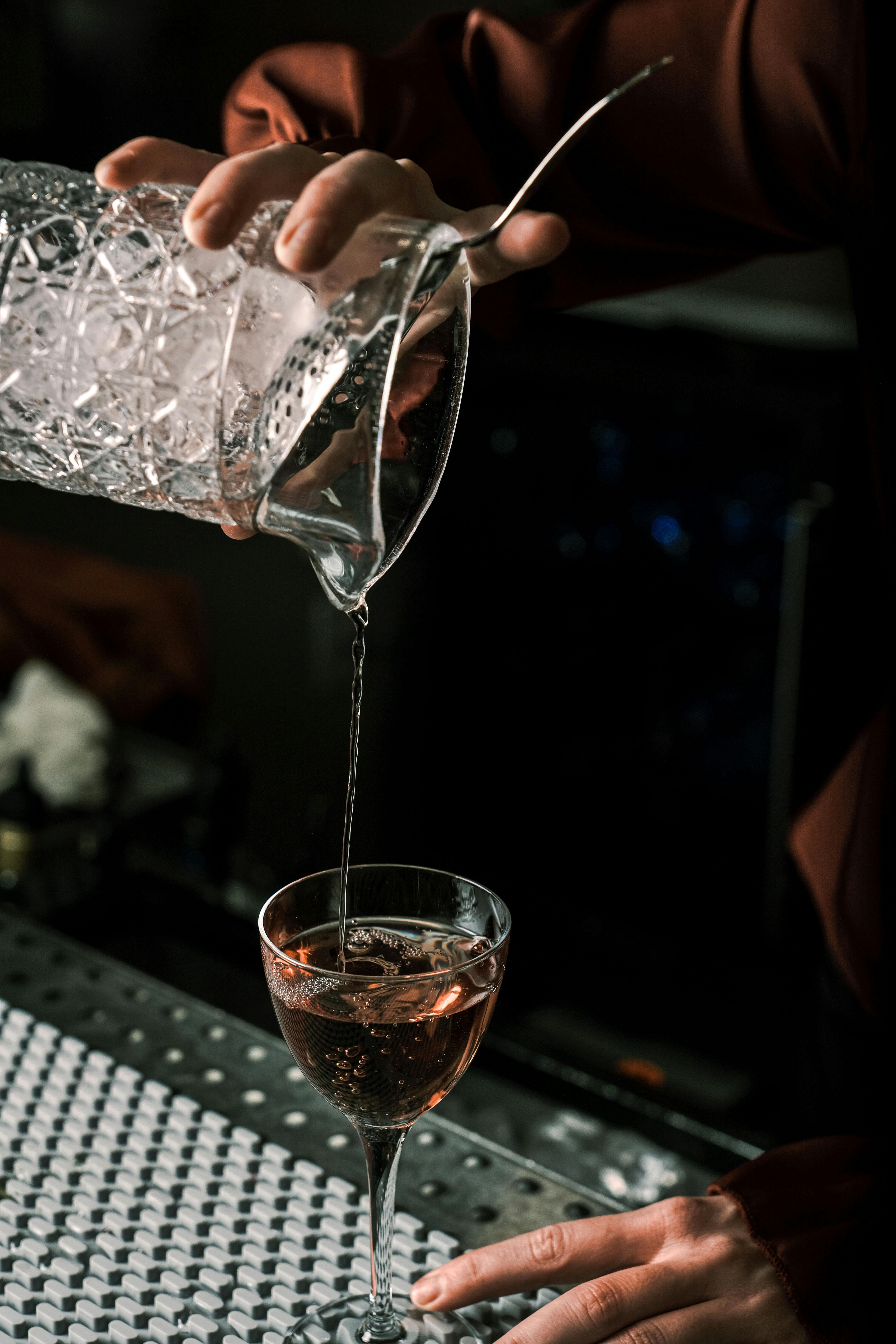 bartender pouring cocktail in dimly lit bar