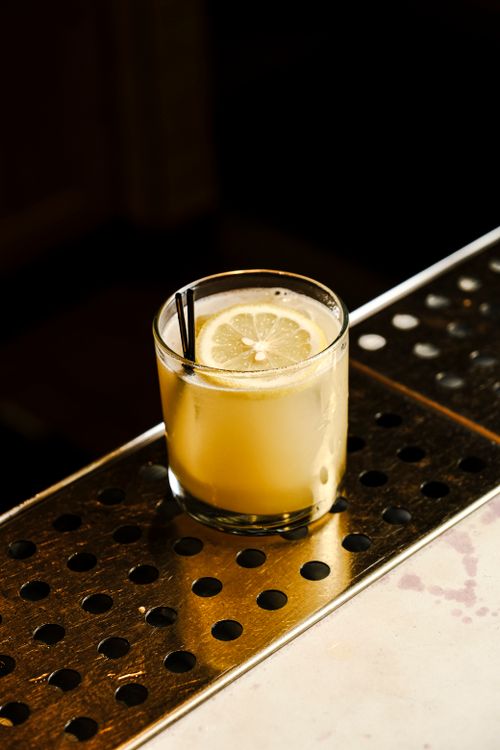 Free A citrus cocktail garnished with a lemon slice on a stylish metal bar counter. Stock Photo