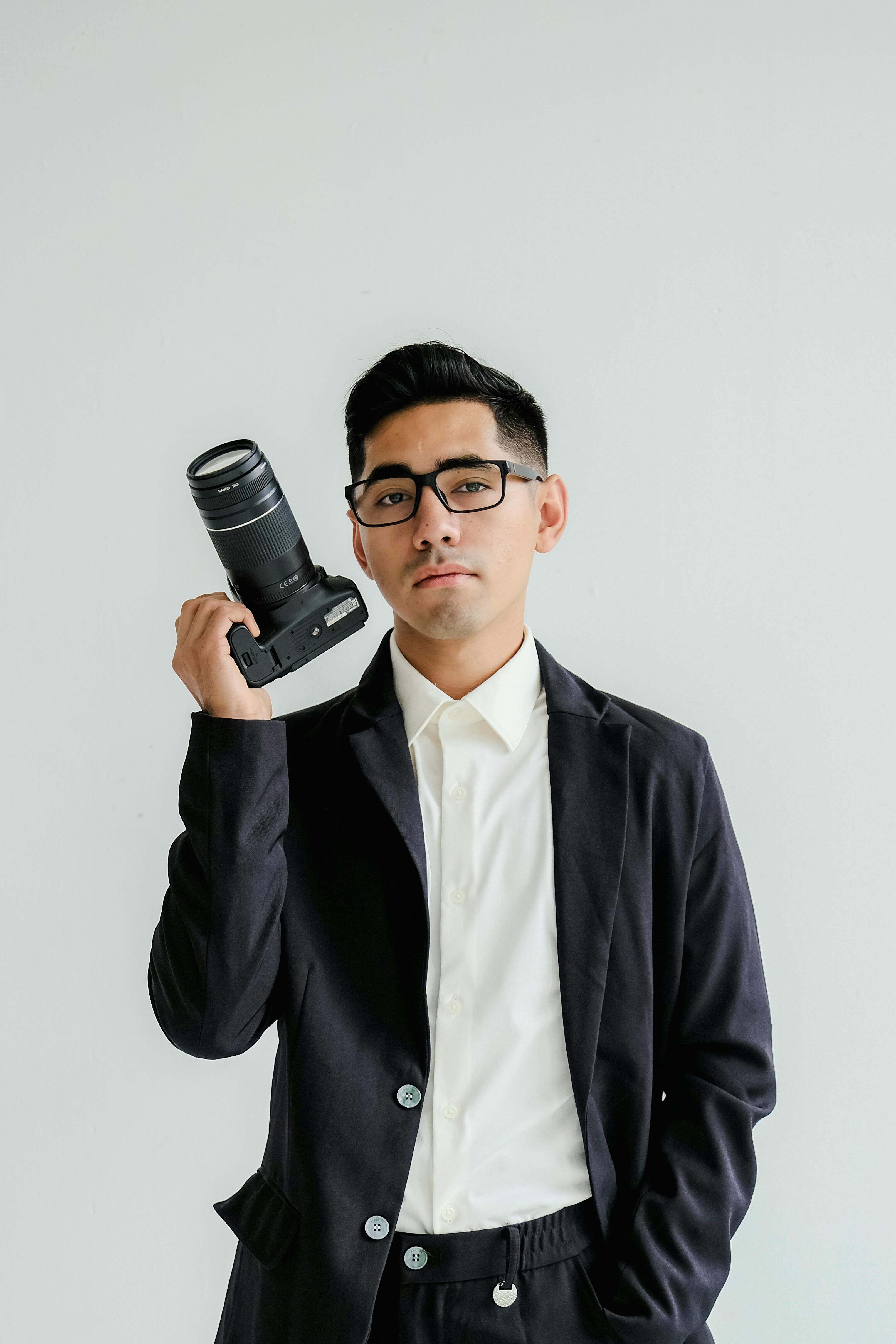 Bezpłatne Portret profesjonalnego fotografa trzymającego aparat i emanującego pewnością siebie. Zdjęcie z galerii