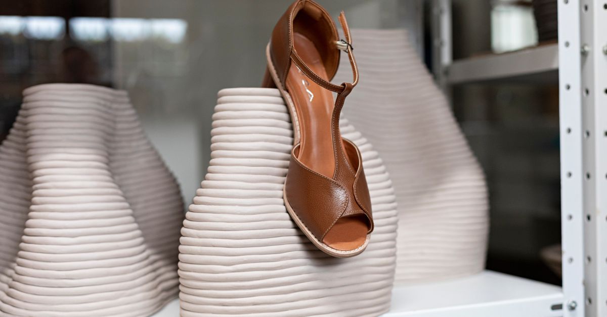 A sophisticated brown leather shoe displayed atop a textured ceramic vase for a stylish effect.