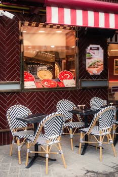 Charming outdoor cafe setting with zebra stripe chairs and various pizzas on display.
