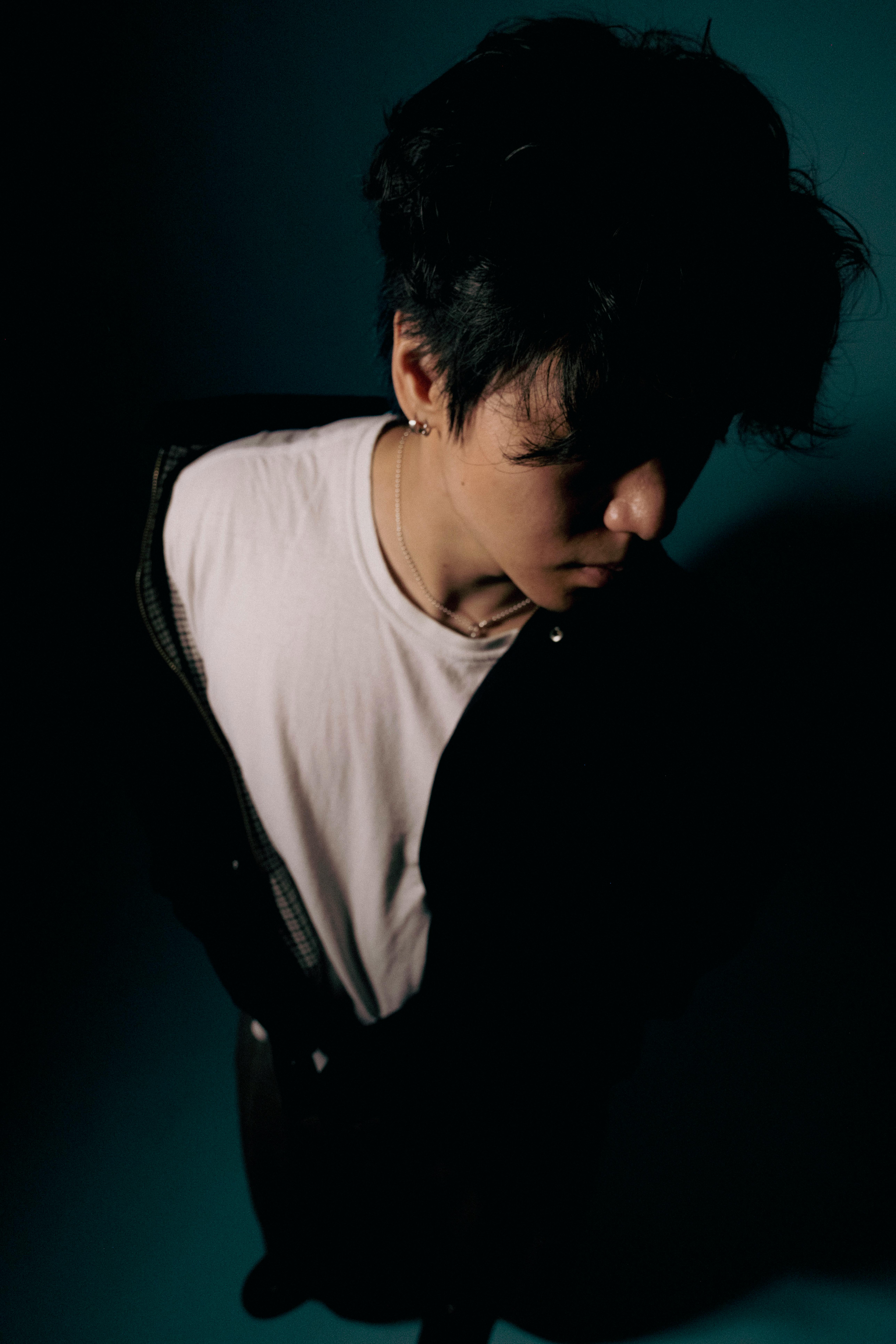 Dramatic low-light portrait of a man with a shadowed face in a studio setting.