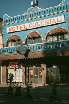 A vibrant blue hotel facade with colonial architecture in the warm afternoon sun.