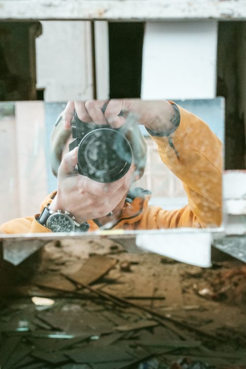 Free Creative portrait of a photographer capturing a reflection using a DSLR in a broken mirror. Stock Photo