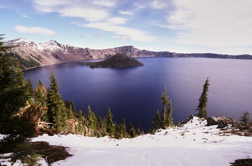 Free Stunning perspective of Crater Lake surrounded by snow-capped mountains in Oregon. Stock Photo