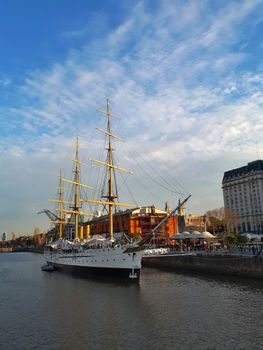 A majestic historic ship moored in Puerto Madero, Buenos Aires, against a vibrant sky.