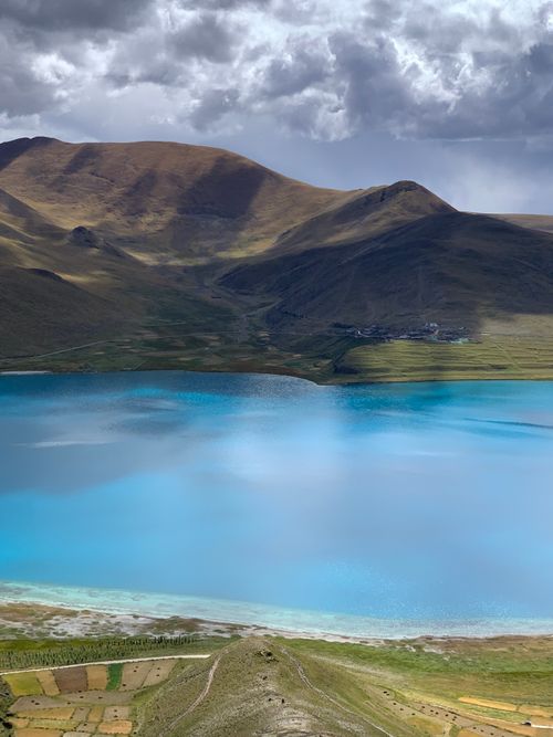 Free A tranquil mountain lake with vibrant blue water under a dramatic cloudy sky. Stock Photo