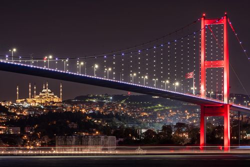 Free Illuminated Bosphorus Bridge spanning the cityscape of Istanbul at night with city lights and mosques. Stock Photo