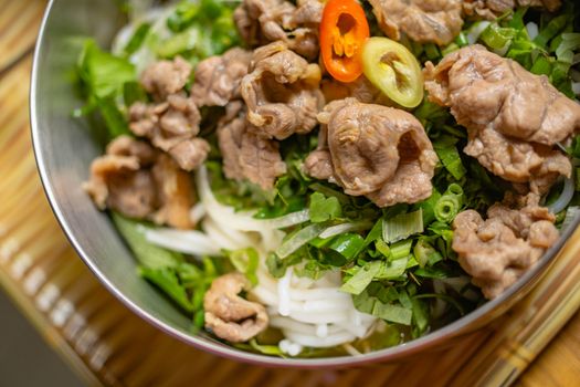 Fresh Vietnamese beef noodle salad with herbs and peppers in a bowl. Perfect for healthy eating enthusiasts.