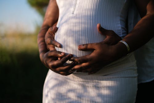 Free Hands Of A Couple Embracing The Baby Inside Her Growing Belly Stock Photo