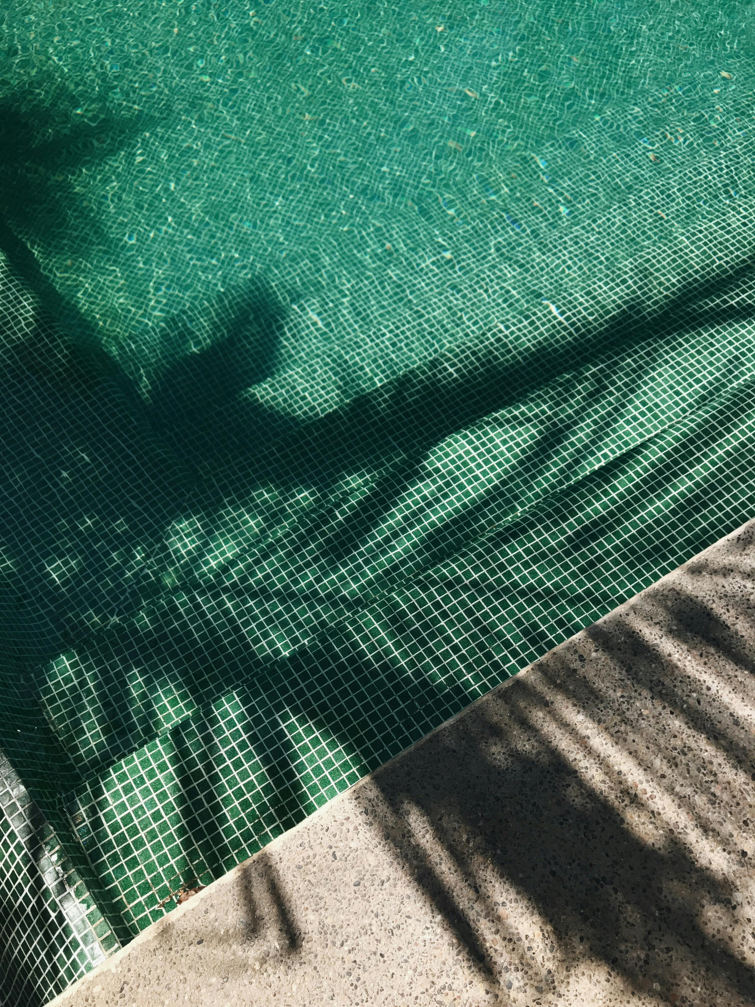 Palm tree shadows cast over a turquoise swimming pool in Nayarit, Mexico, creating a serene tropical vibe.