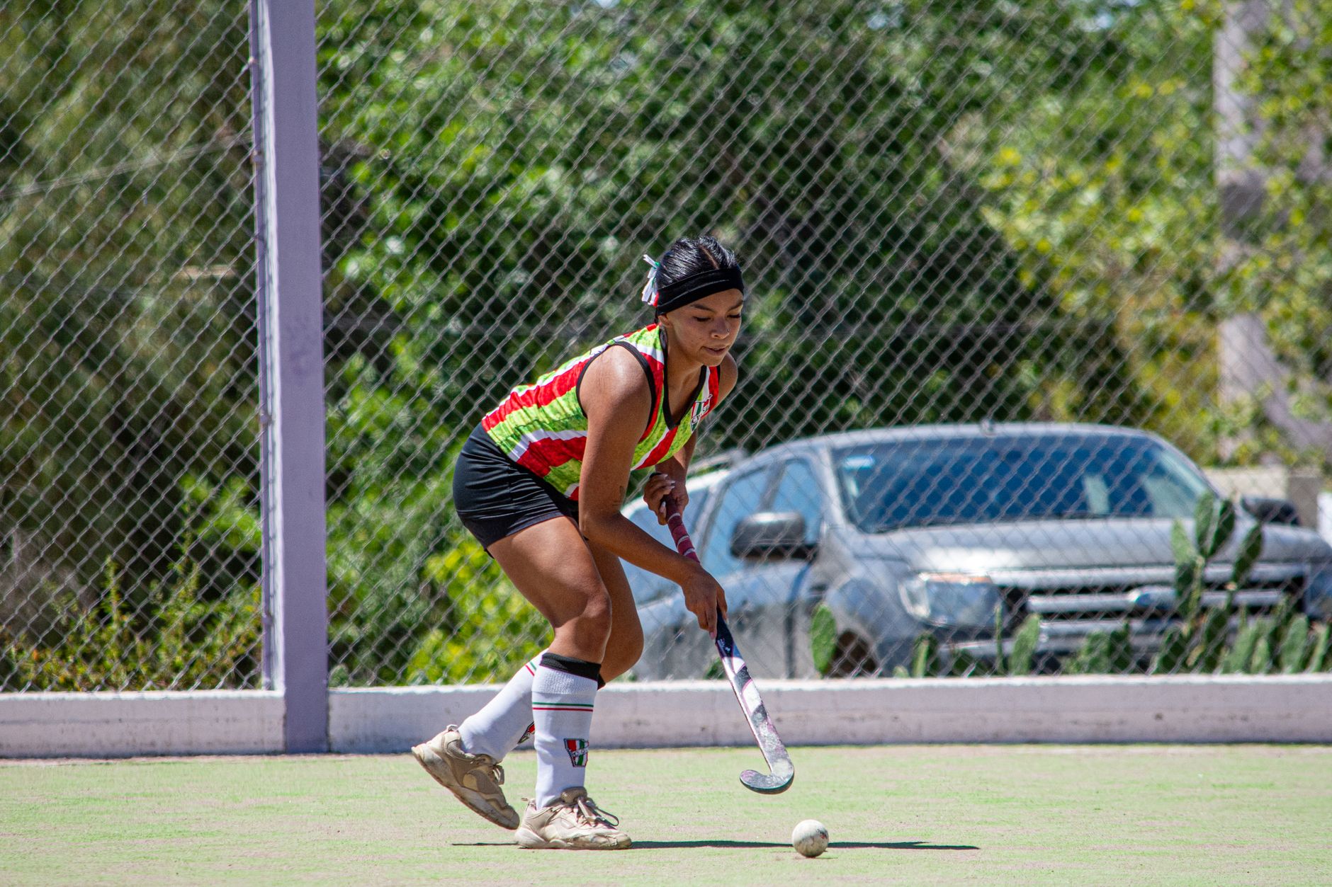 Female field hockey player in action on a sunny outdoor field.