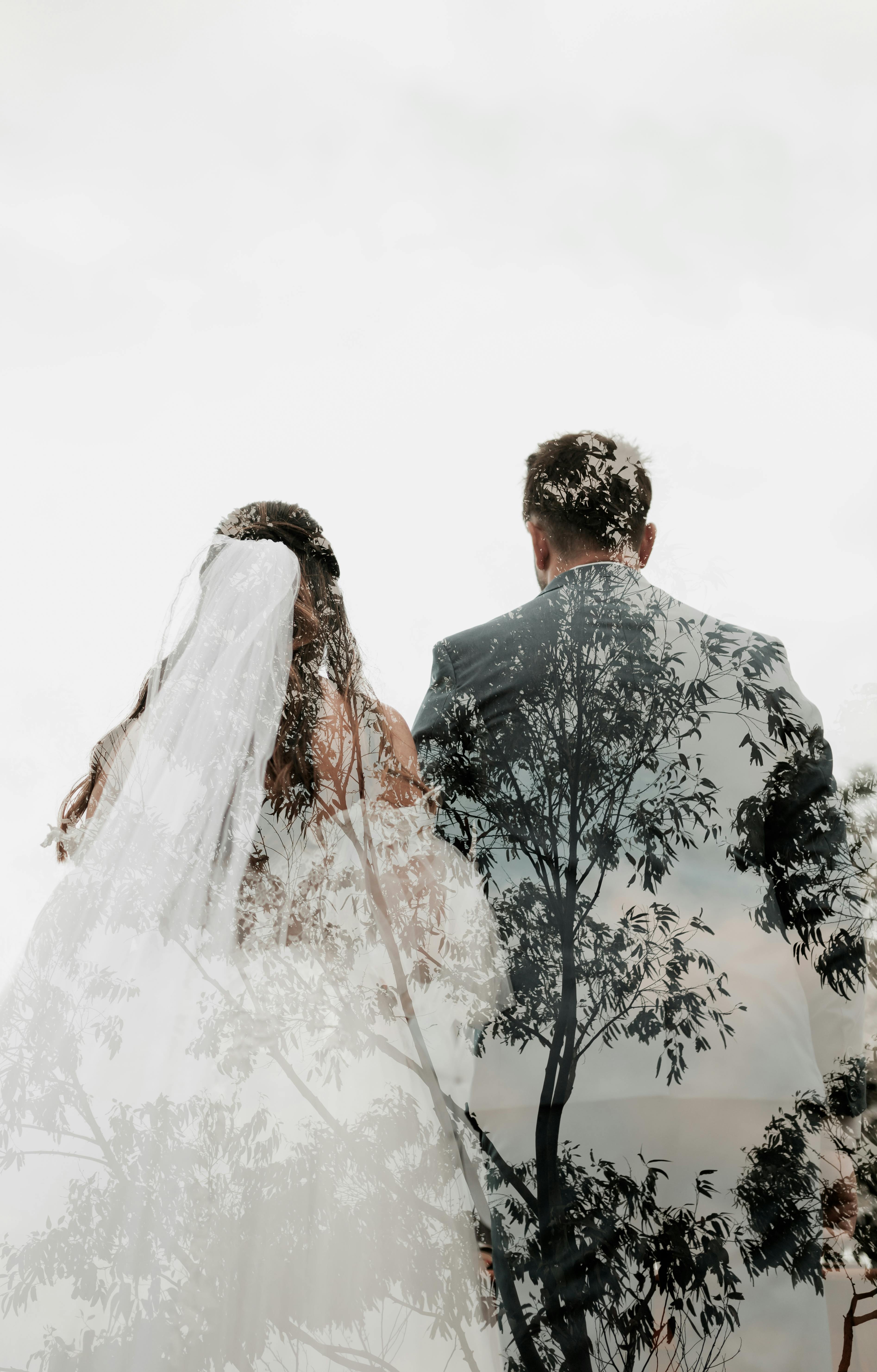 Double exposure of a bride and groom with tree silhouette, artistic wedding photography.