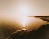 宁静的日落景色，俯瞰平静的海水和沙质悬崖，营造出宁静的海景