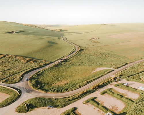 Free Scenic aerial view showcasing winding country road amidst lush green fields in rural landscape. Stock Photo