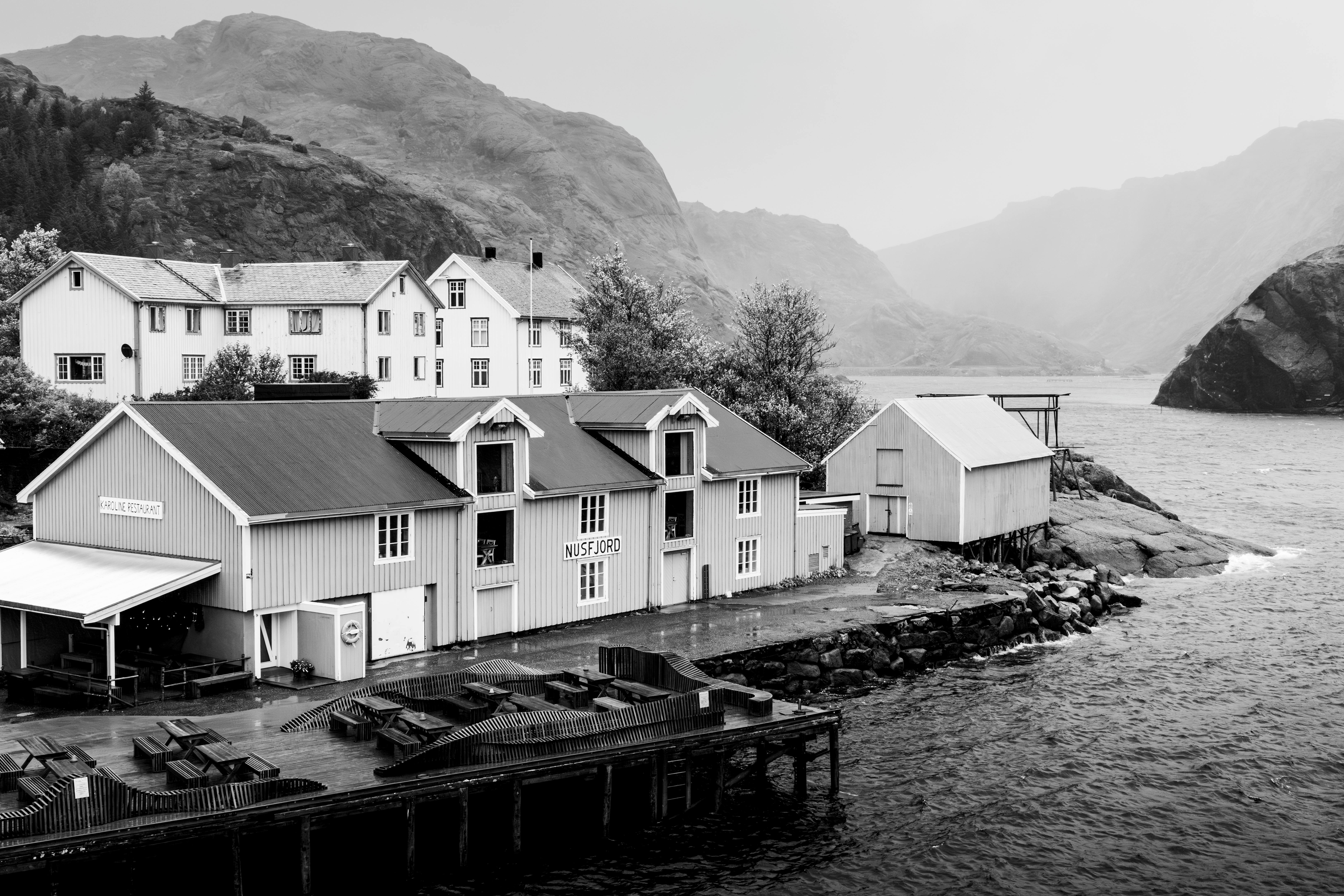 Scenic view of Nusfjord, a historic fishing village by the sea, captured in black and white.