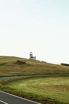 一座灯塔孤零零地矗立在乡村的草小山上