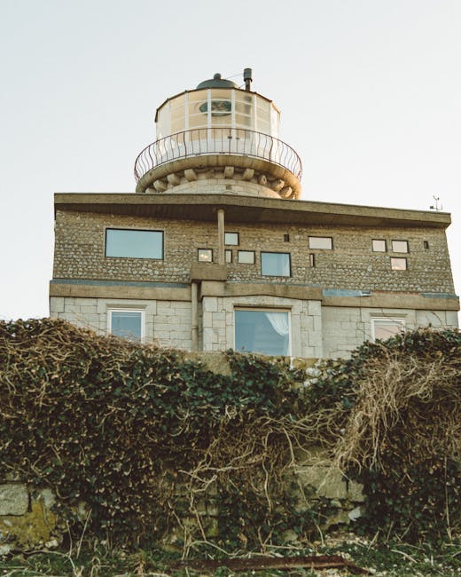 A rustic lighthouse with a stone facade and vines, captured in daylight.