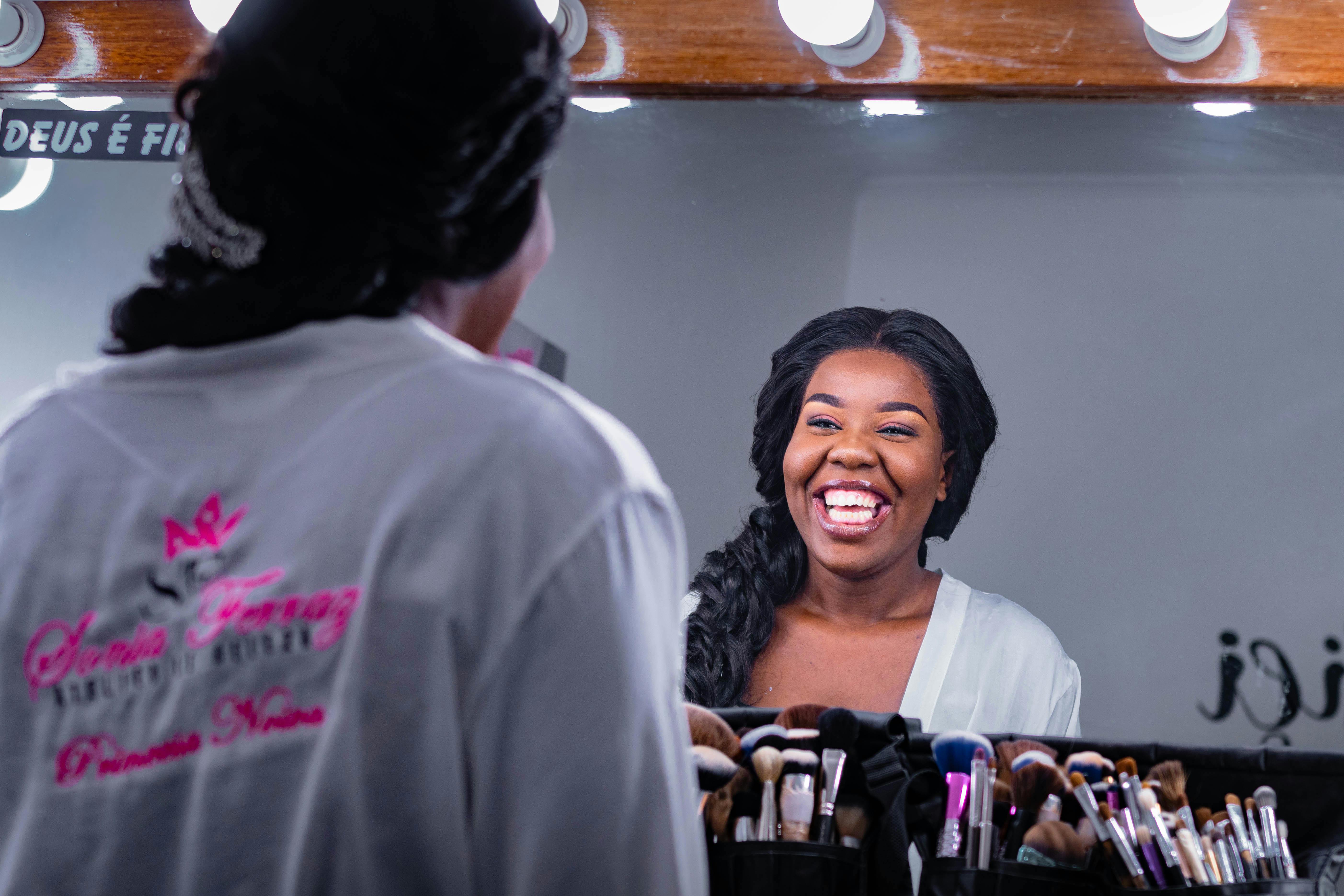 室内梳妆镜的倒影中，一位黑人妇女正快乐地笑着