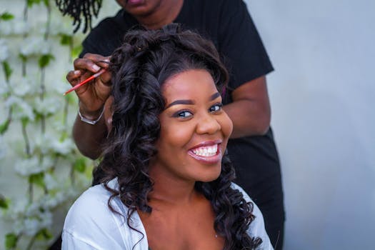 A joyful woman smiling during a hair styling session indoors, capturing happiness.