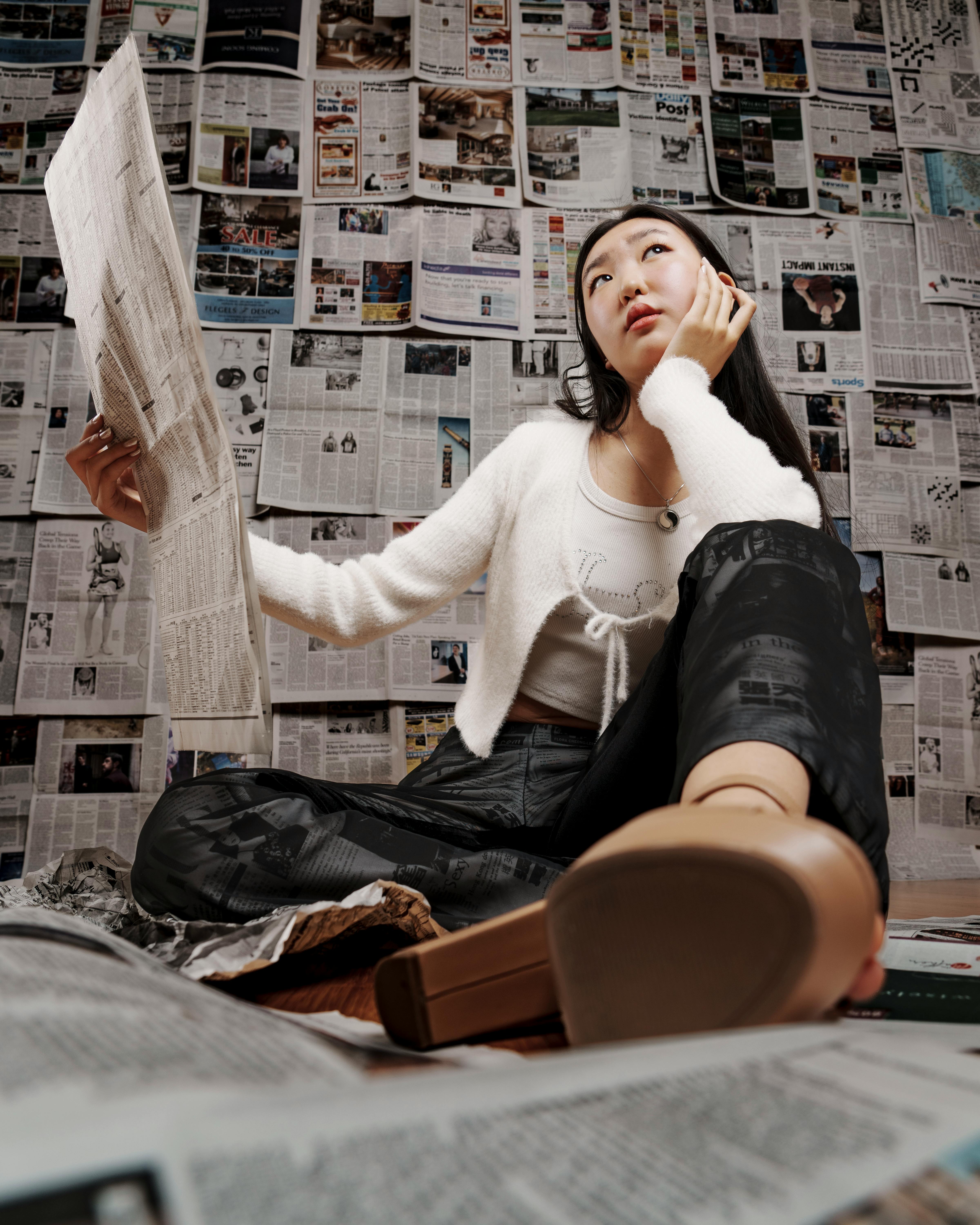 young woman reading newspaper indoors