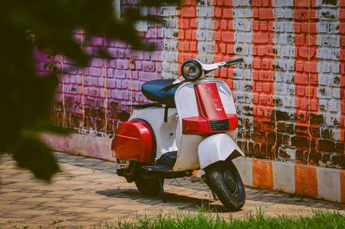 Free Retro red and white scooter parked by a vibrant, artistic wall outdoors. Stock Photo