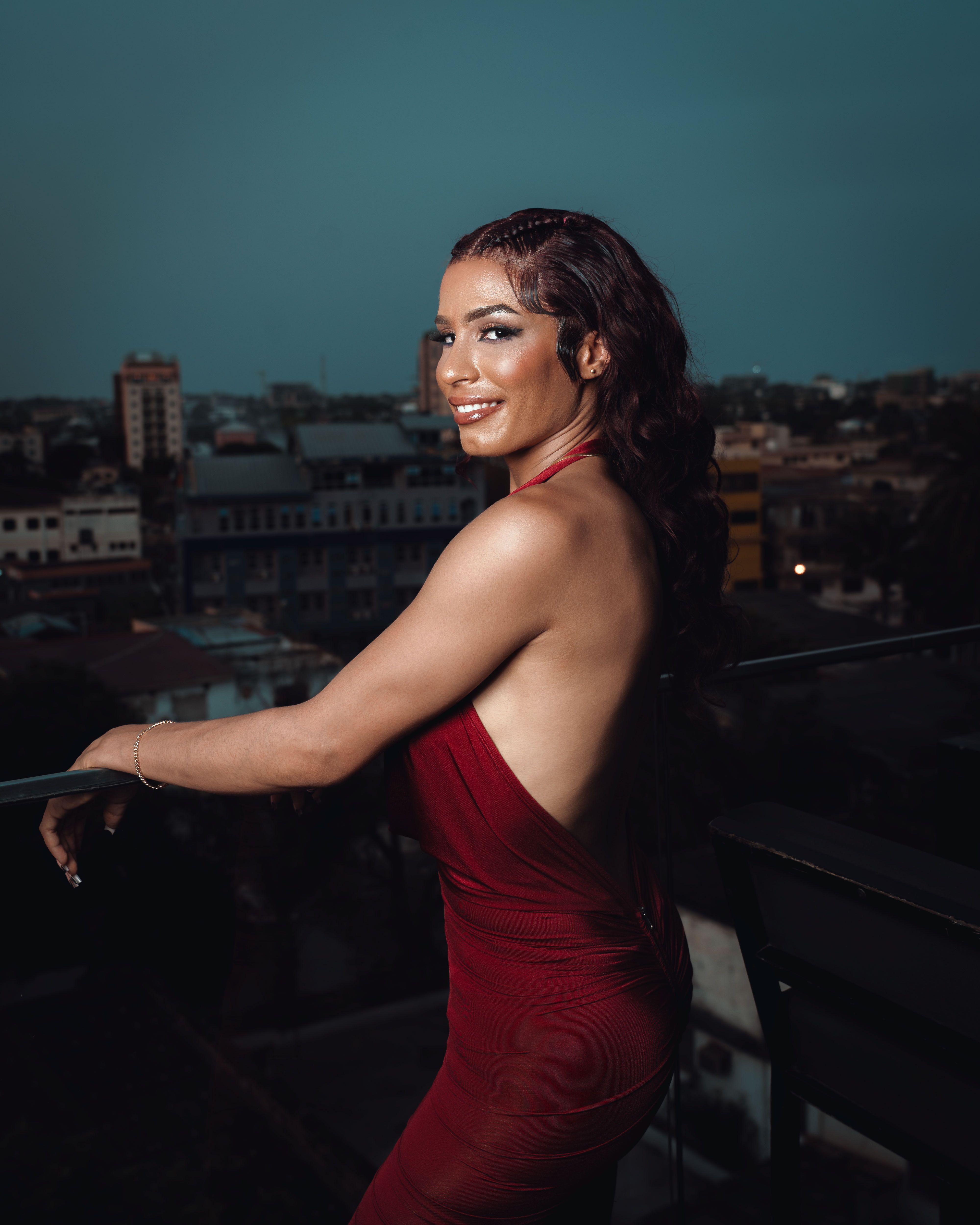 Elegant woman in red dress on urban balcony at dusk · Free Stock Photo