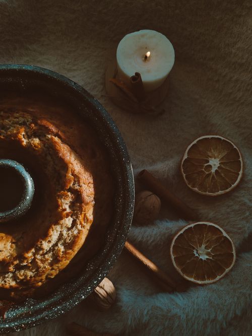 Free Rustic bundt cake with candle and dried oranges, perfect for cozy autumn evenings. Stock Photo