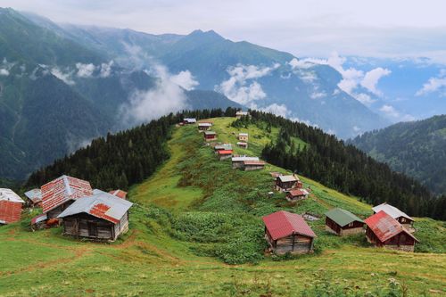 Free Aerial view of a picturesque mountain village with rustic wooden cabins amidst lush greenery. Stock Photo