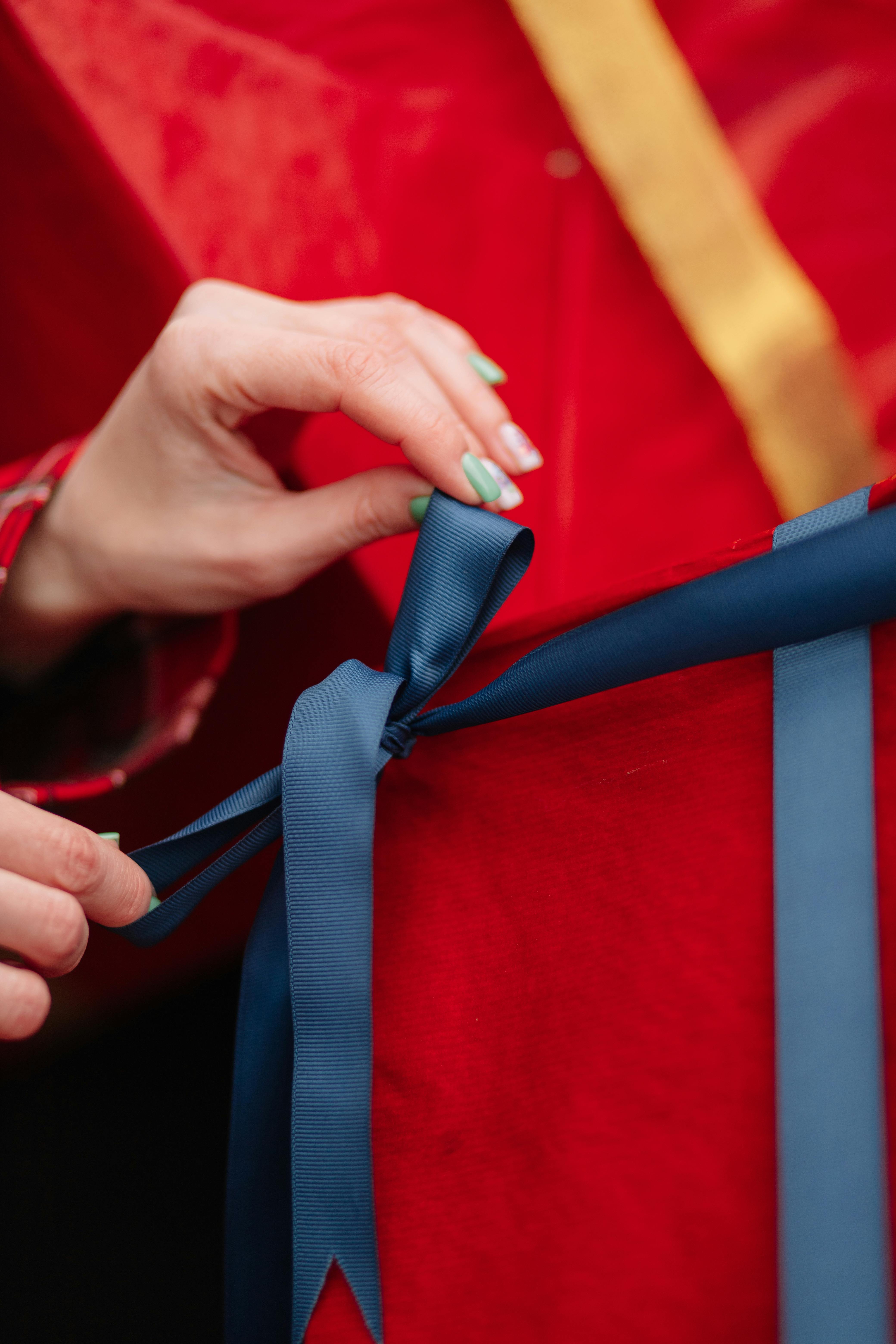 Primo piano di mani che legano un nastro blu su scatola rossa