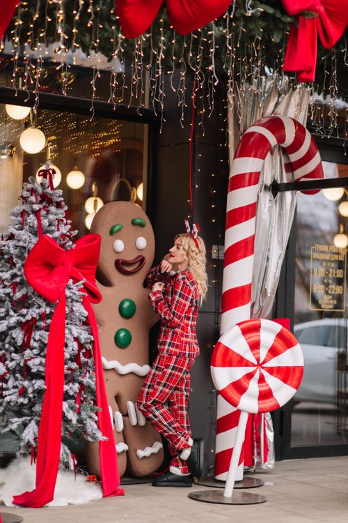 Free Woman in pajamas with festive gingerbread and candy decorations outside a shop during Christmas. Stock Photo