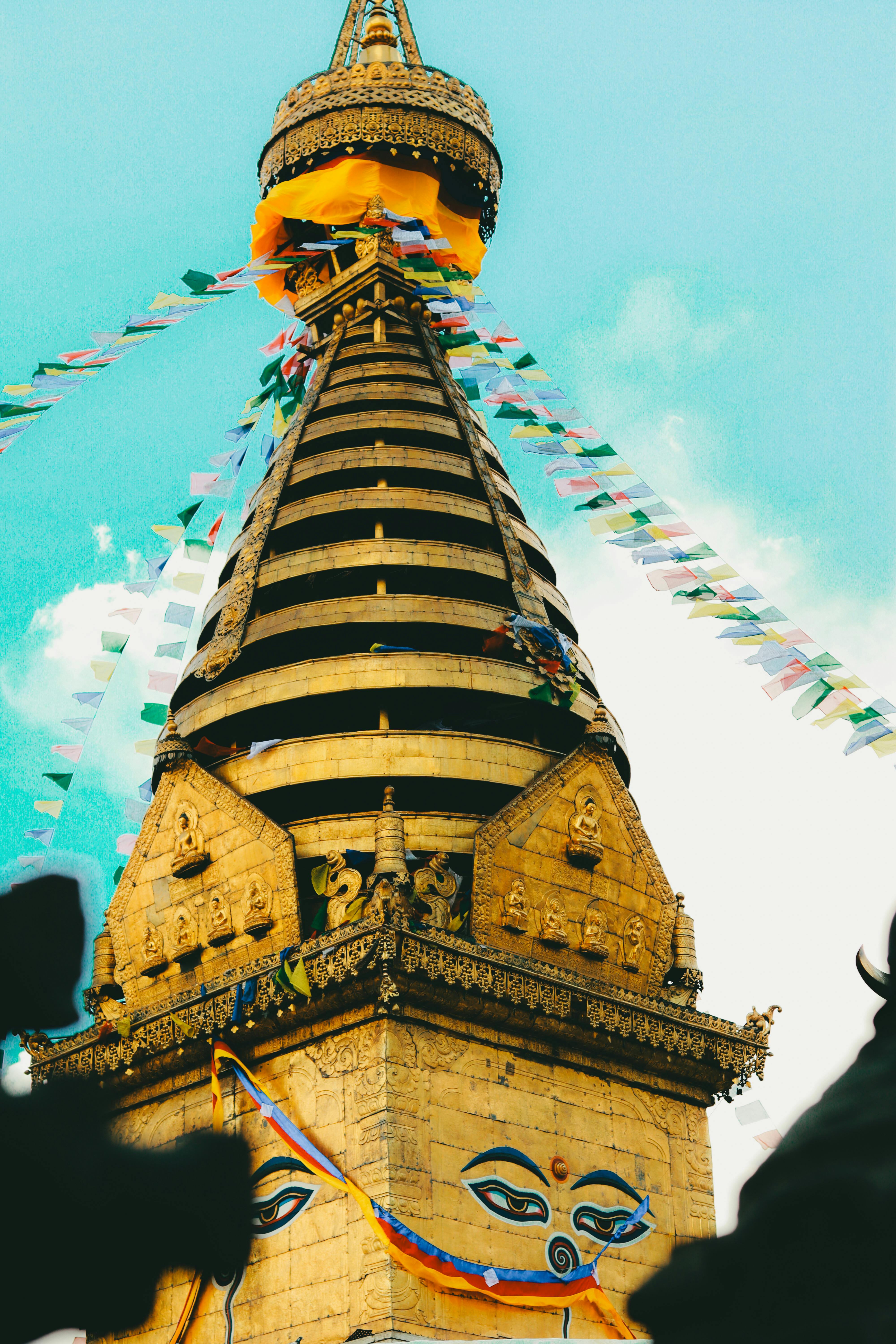 Golden Swayambhunath Stupa topped with colorful prayer flags against blue sky.