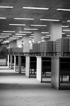 Black and white photo of a spacious library interior featuring rows of wooden desks and bookshelves.