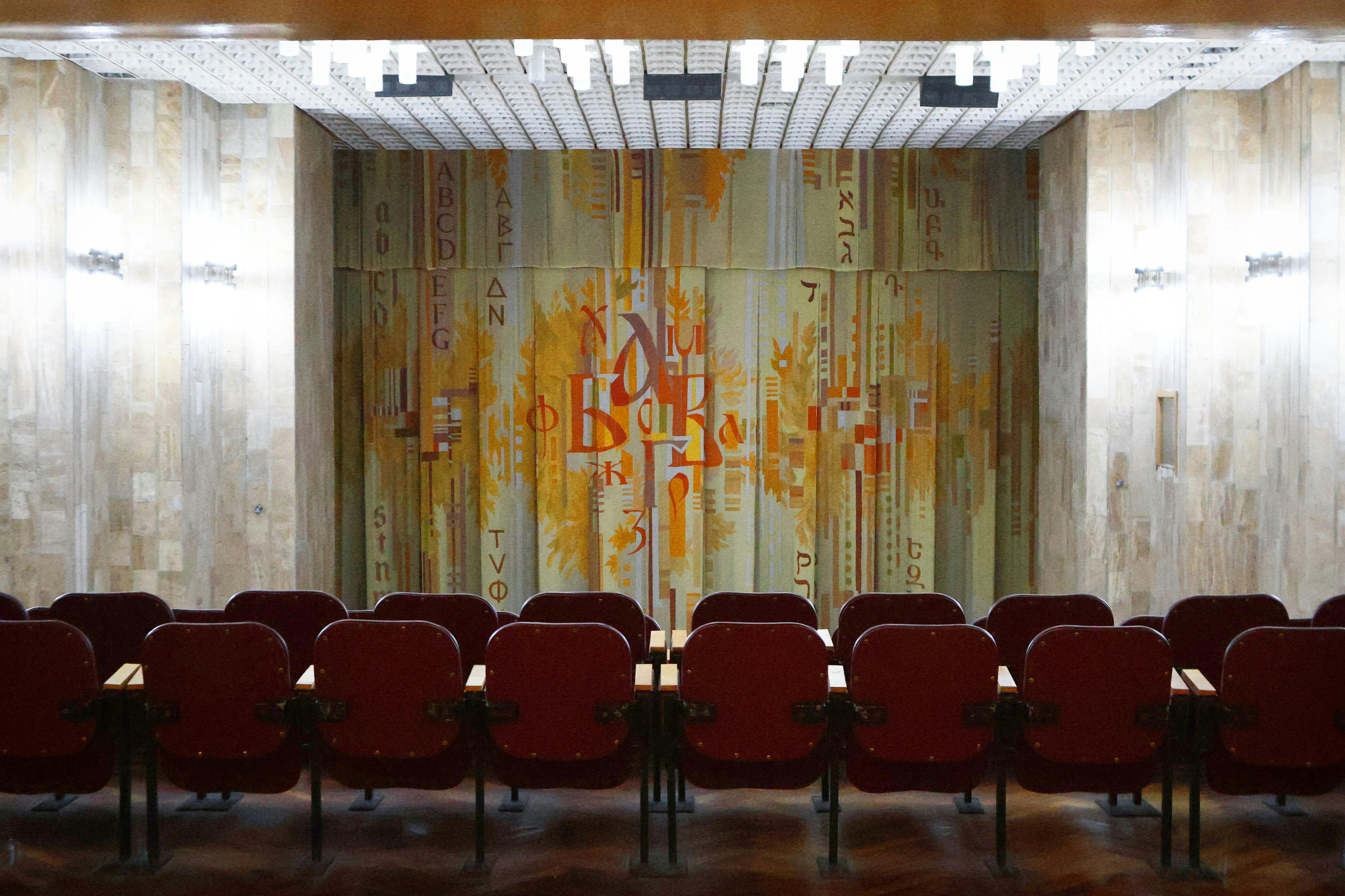 Gratis Sala teatrale vuota con decorazioni vintage e sipario con opere d'arte astratte, che creano un'atmosfera nostalgica. Foto a disposizione