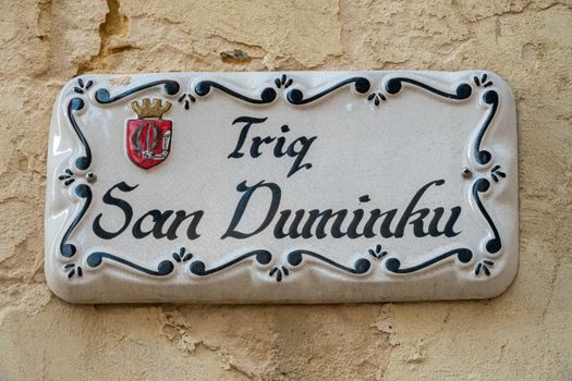 Decorative street sign of Triq San Duminku, Malta with intricate lettering and emblem.