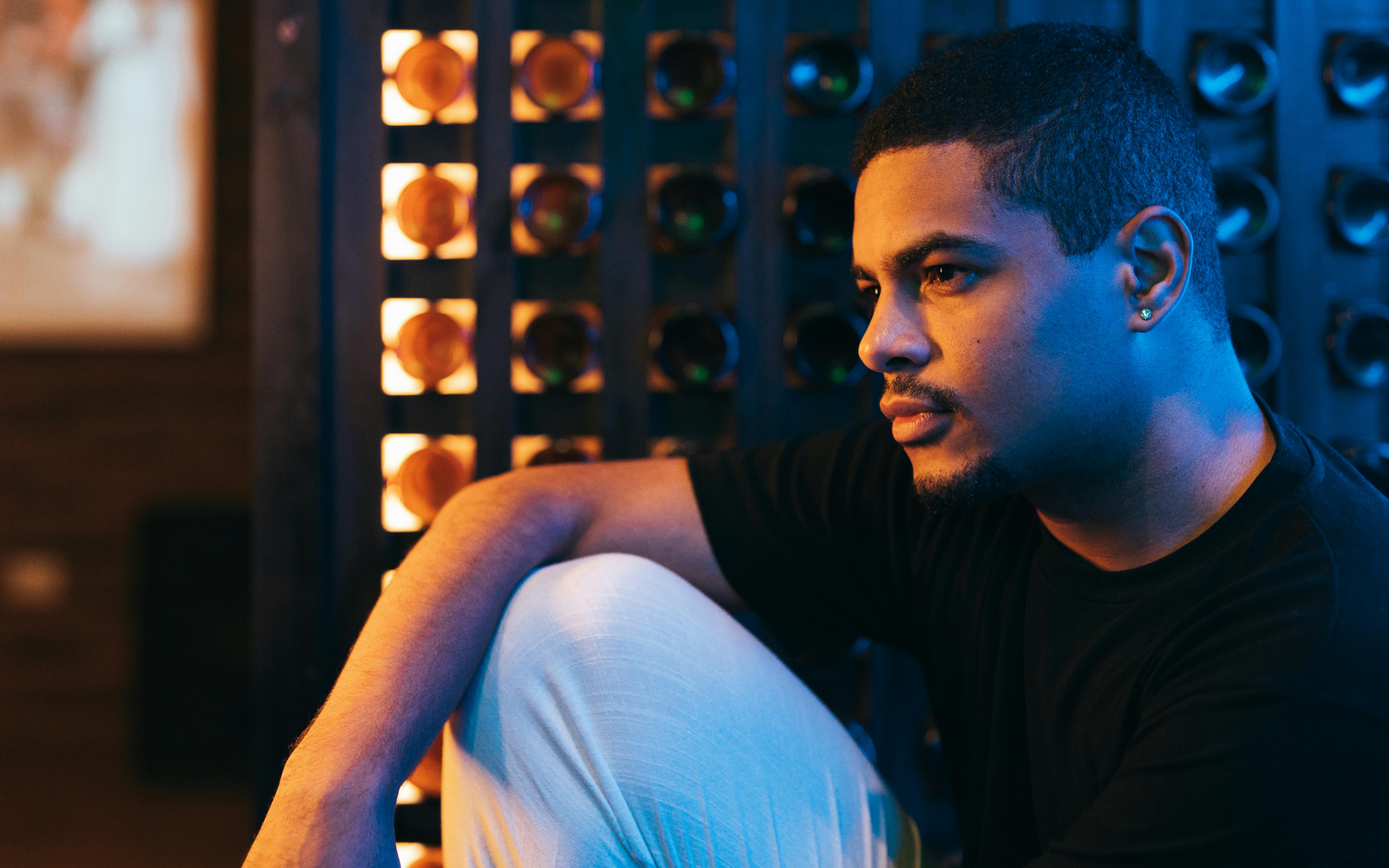 Portrait of a young man sitting indoors under blue neon lights in Buenos Aires.